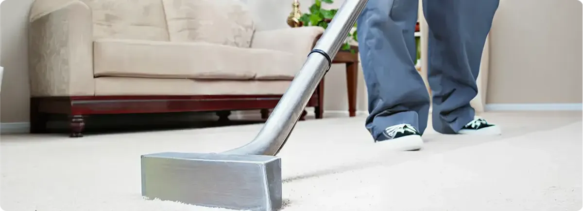 Carpet cleaning technician using a hot-water extraction wand on a light-colored carpet in a living room, Columbus, OH.