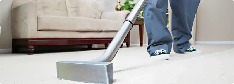 Carpet cleaning technician using a hot-water extraction wand on a light-colored carpet in a living room, Columbus, OH.