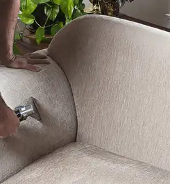 Professional upholstery cleaner deep-cleaning a fabric sofa with a handheld extraction tool and hose Columbus, OH.